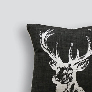 Black pillow with a white deer head design on a light gray background