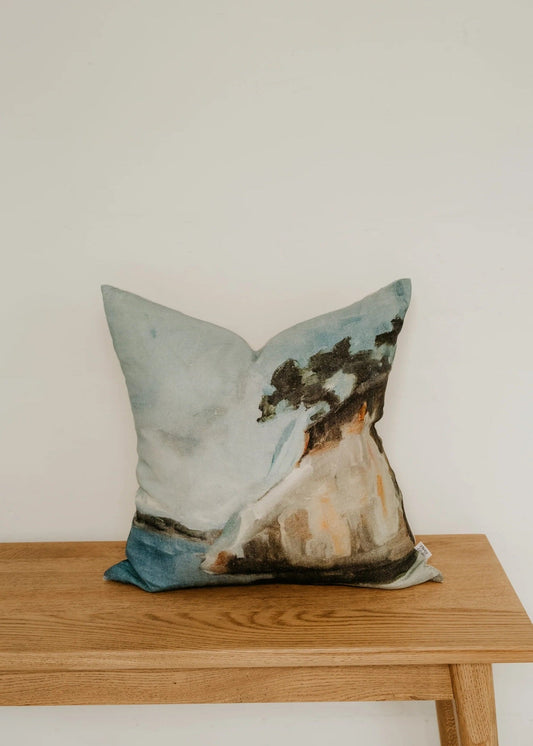 Decorative pillow with a nature design on a wooden bench against a white wall