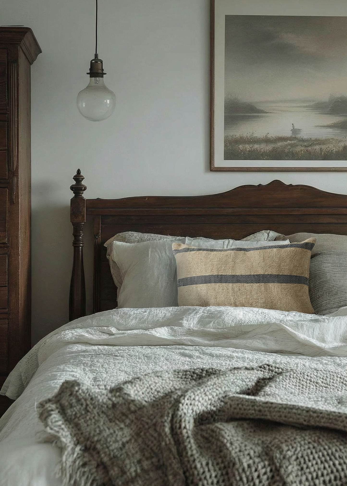 Cozy bedroom with wooden bed, textured bedding, and framed artwork on the wall.