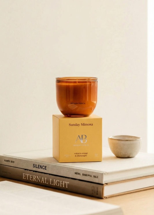 Candle in a amber glass on top of books with a light background