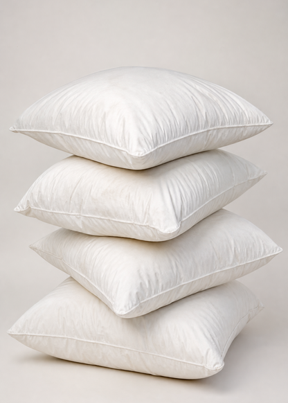 Four white square pillows stacked vertically on a light beige studio background.
