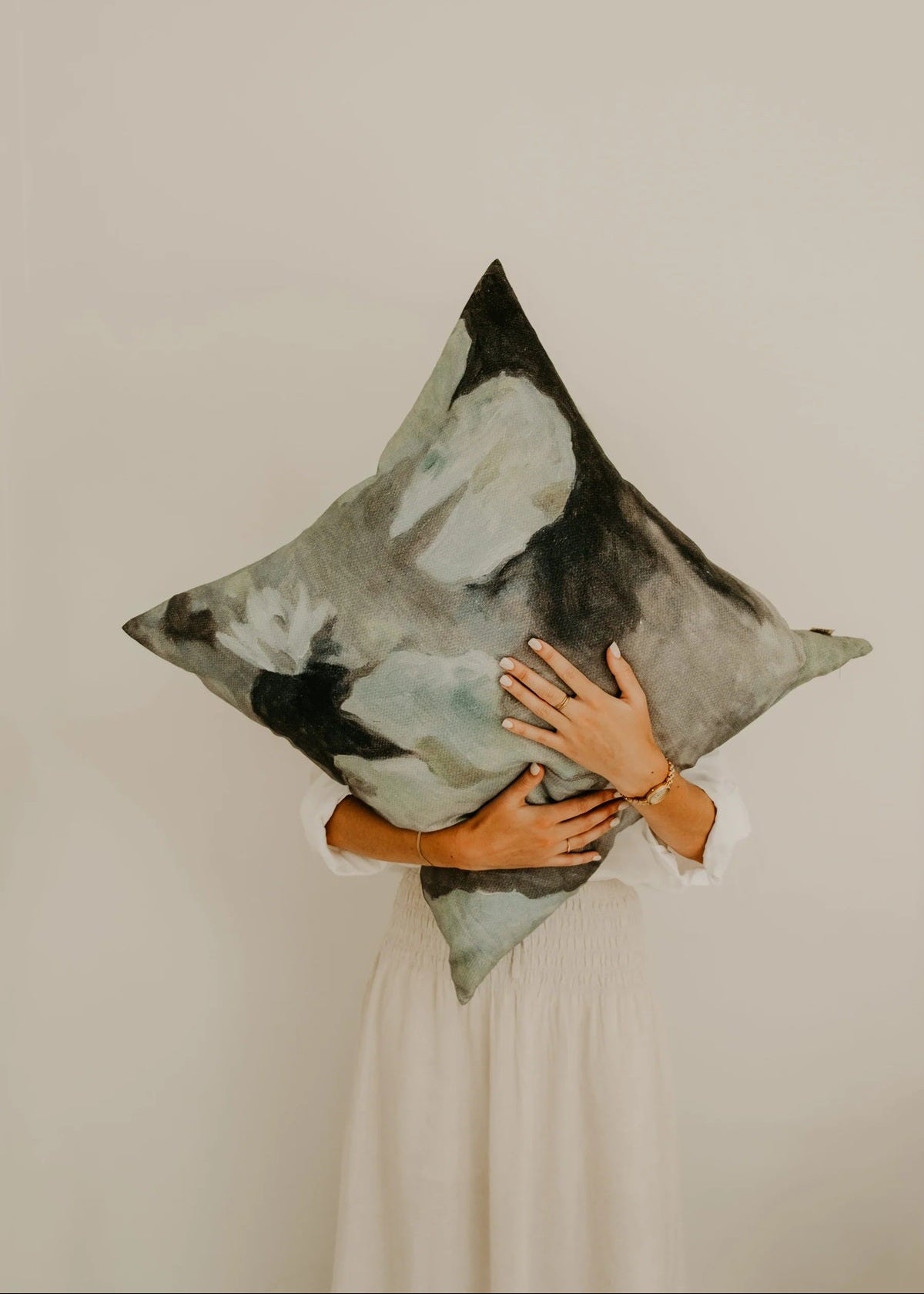 Person holding a decorative pillow against a plain background
