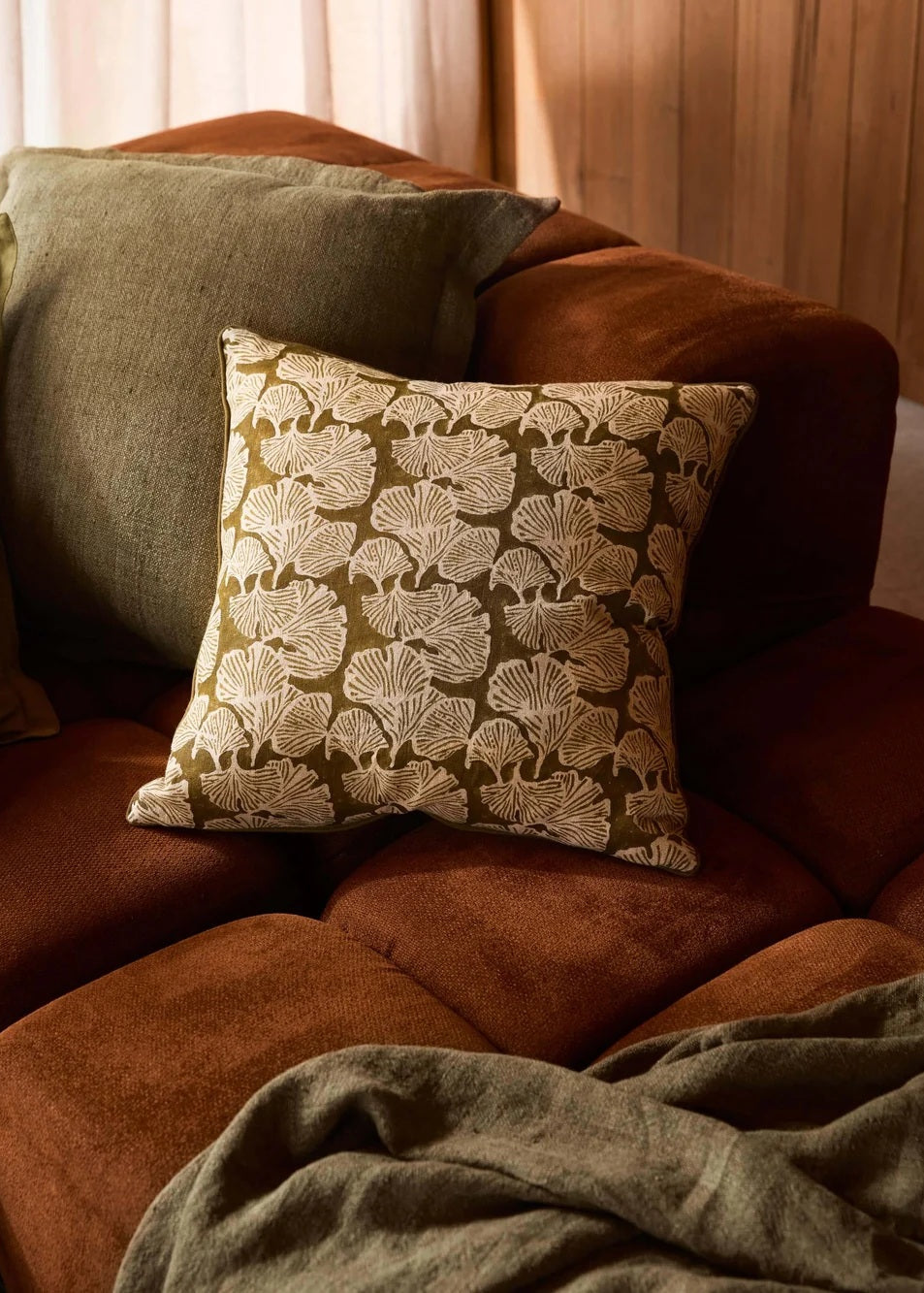 Brown sofa with patterned pillow and green blanket