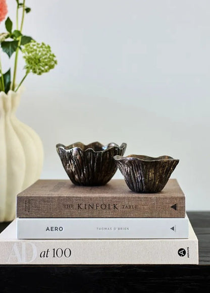 Two decorative bowls on top of books with a vase in the background