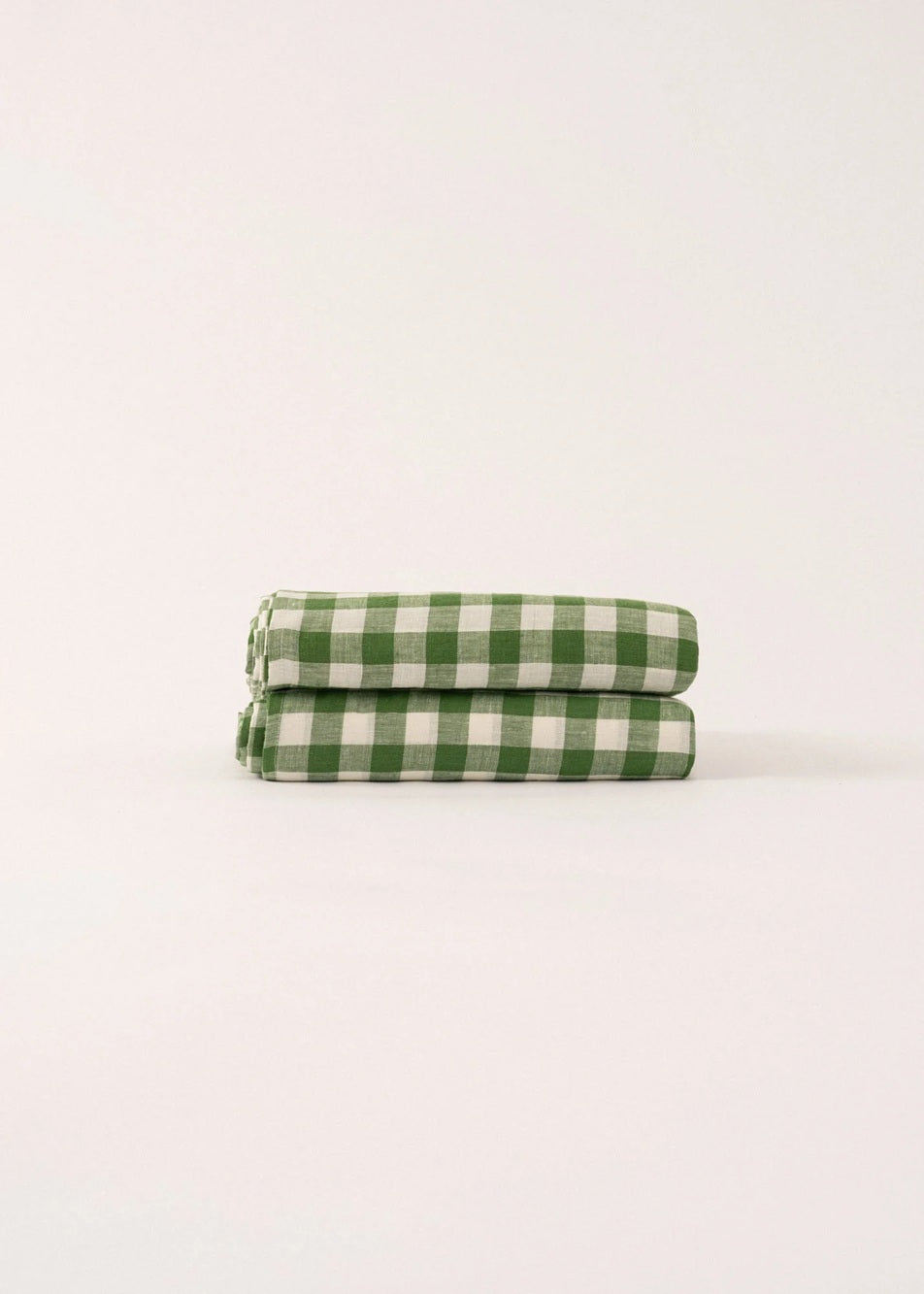 Two green and white checkered towels stacked on a light beige background