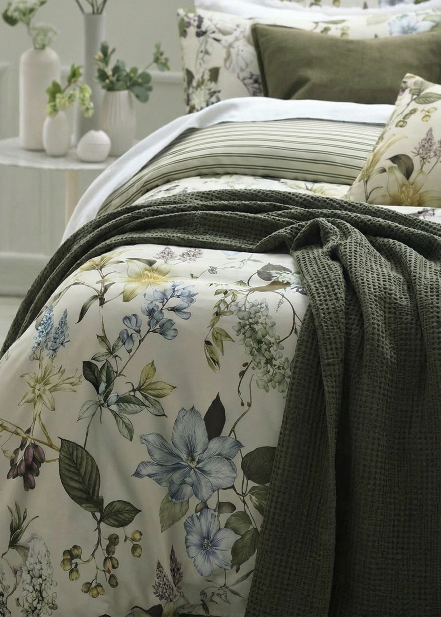 Floral bedding with green throw on a bed in a bedroom setting