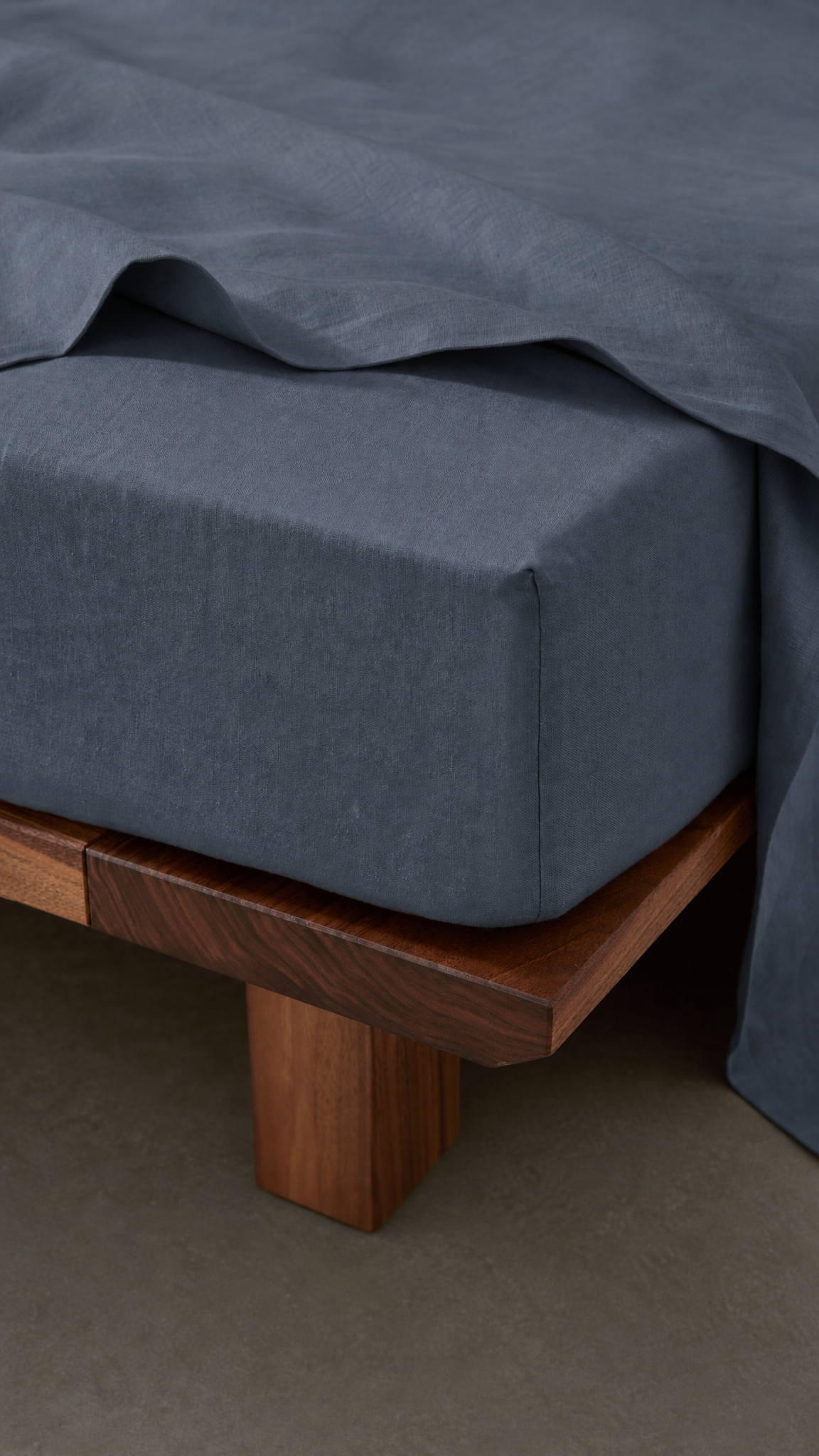 Gray fitted sheet on a wooden bed frame