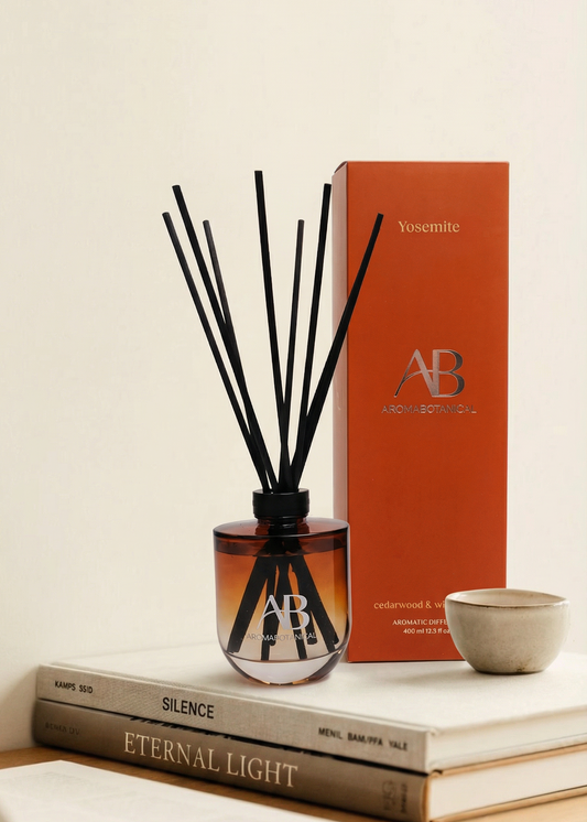 Diffuser with reeds and packaging on books against a light background