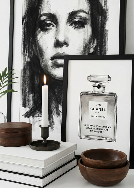 Framed black and white portrait and Chanel perfume bottle art on a shelf with decorative items.