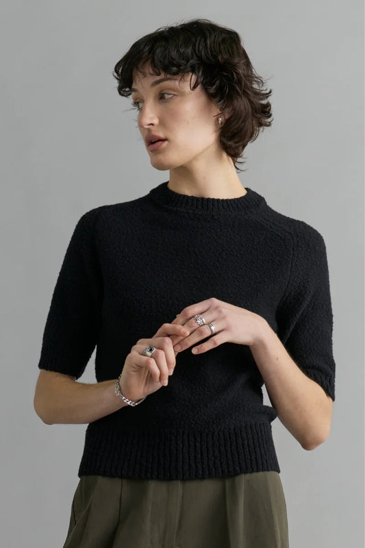 Woman wearing a black sweater against a gray background