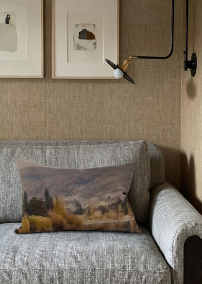 Gray sofa with a decorative pillow, framed art on the wall, and a wall-mounted lamp.
