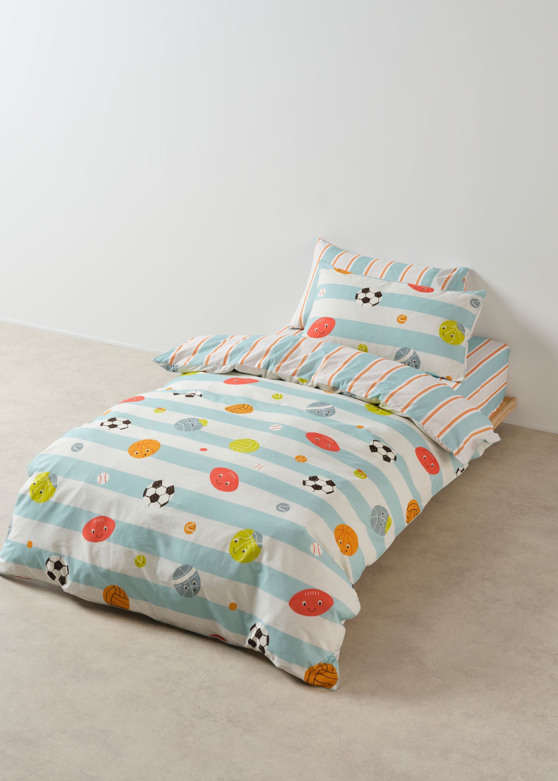 Children's bed with colorful striped bedding featuring polka dots and animal prints.