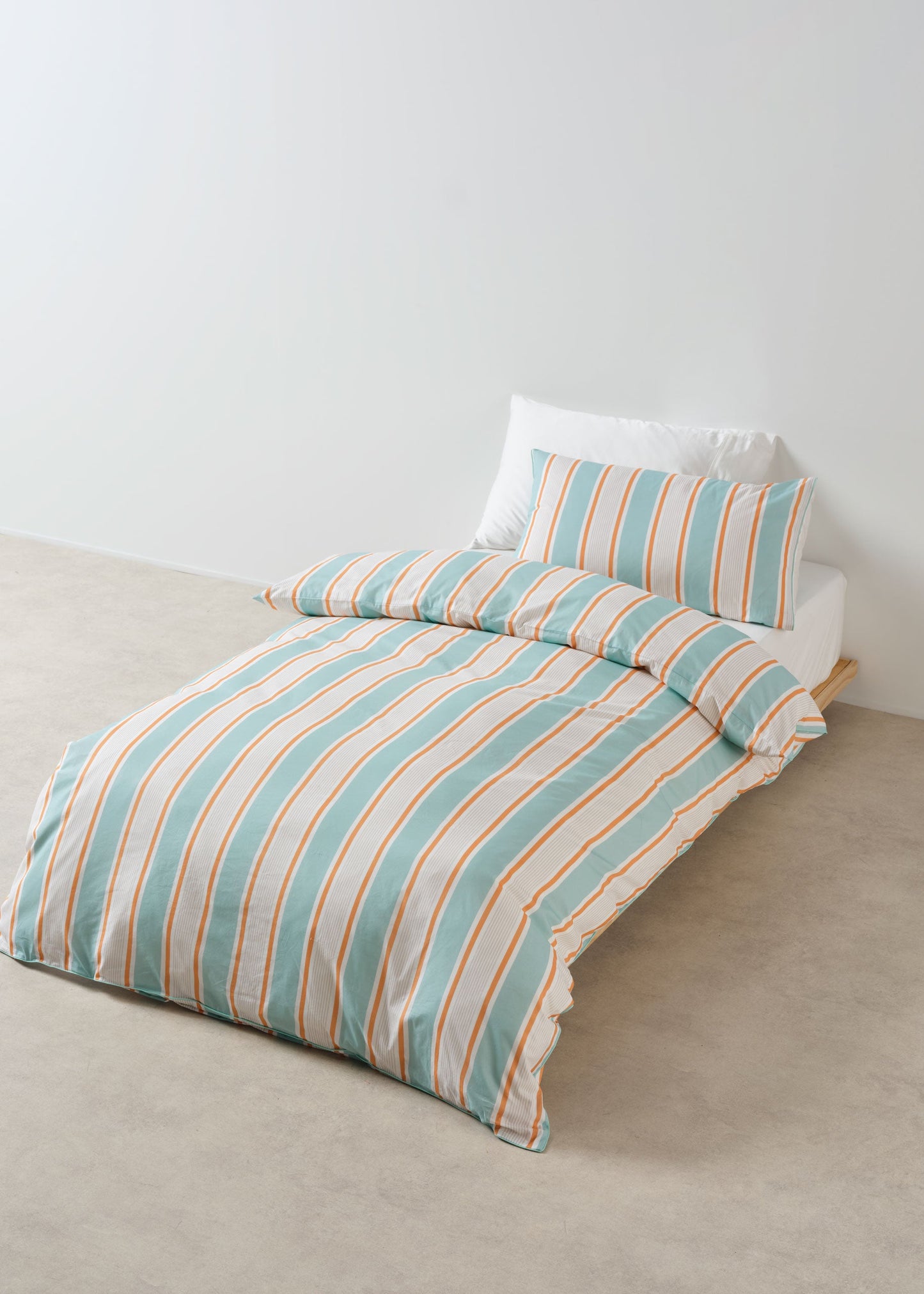 Striped bedspread with matching pillow on a bed against a white wall