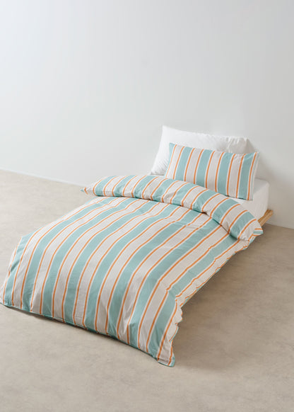 Striped bedspread with matching pillow on a bed against a white wall