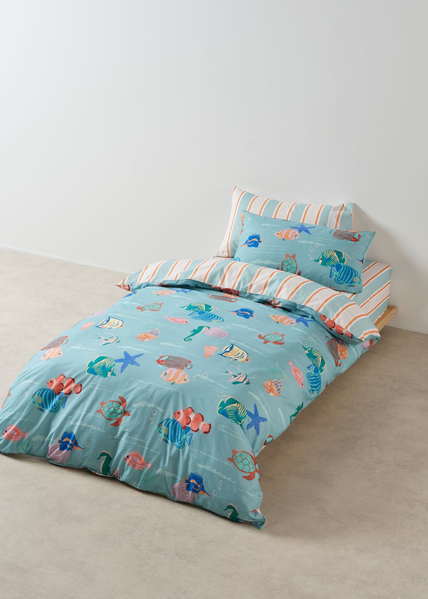 Children's bed with blue bedding featuring sea-themed patterns on a plain background