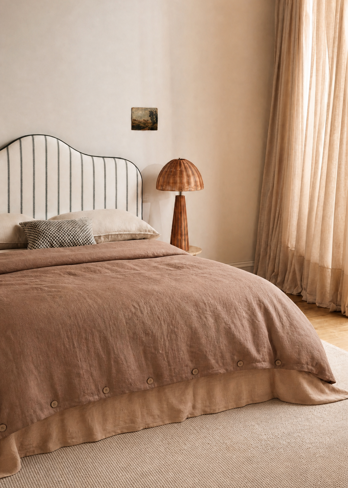 Neatly made bed with brown bedding in a bedroom setting.