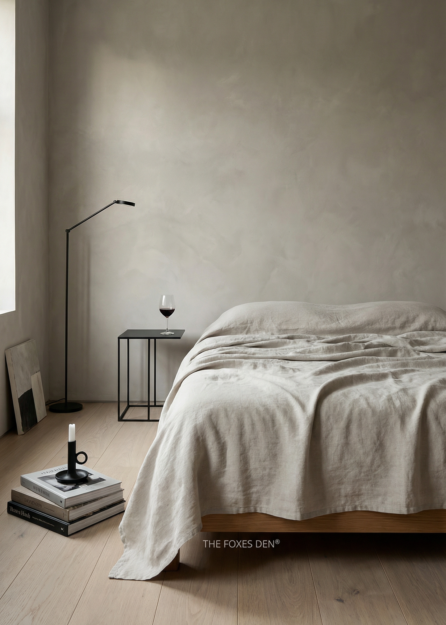 Minimalist bedroom with a bed, side table, and lamp against a plain wall.