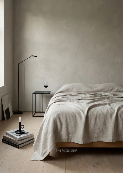 Minimalist bedroom with a bed, side table, and lamp against a plain wall.