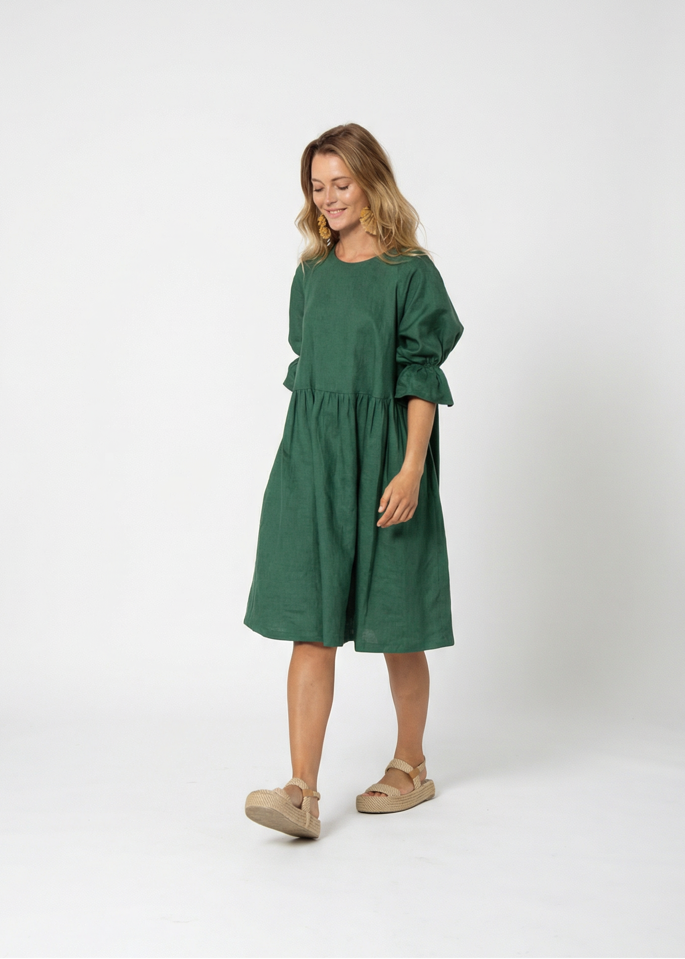 Woman wearing a green dress standing against a white background