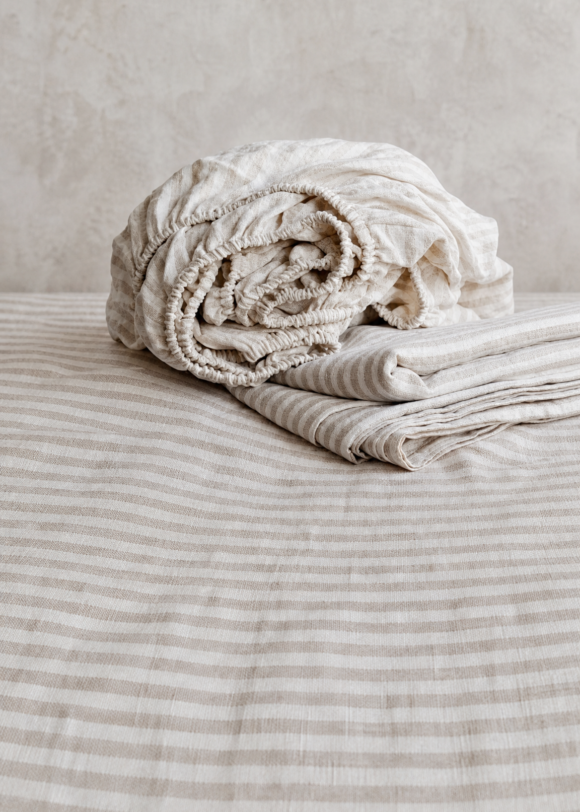 Folded beige towel on a bed with a neutral background