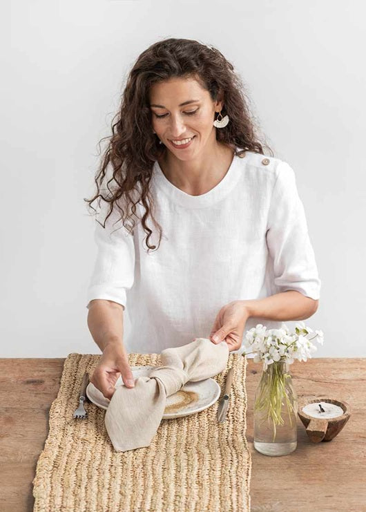 Woman setting a table with a white shirt and a neutral background