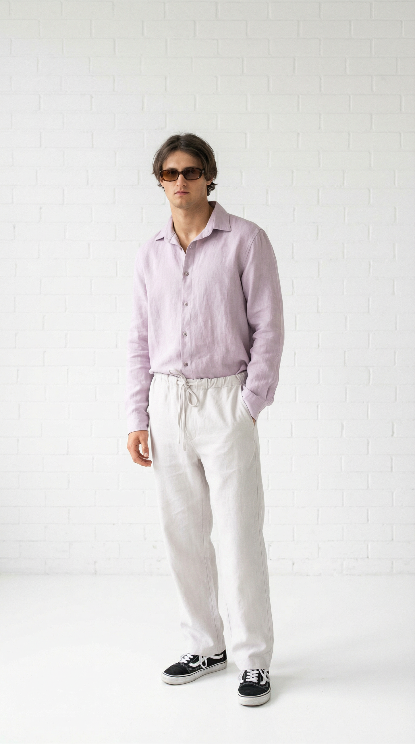 Person wearing a light purple shirt and white pants against a white background