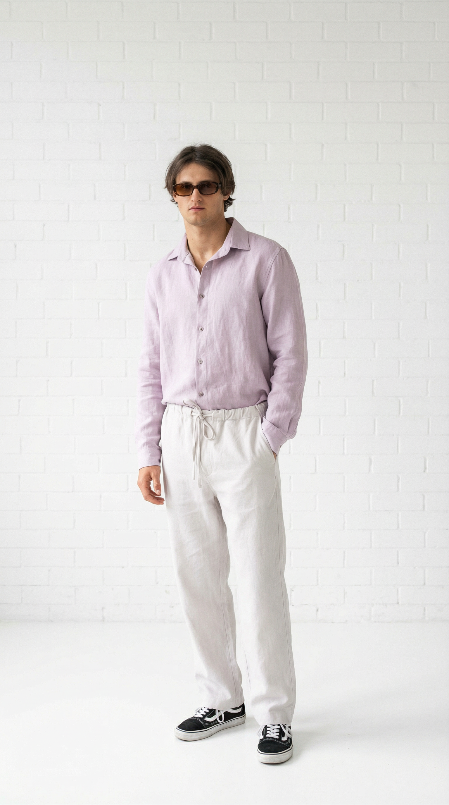 Person wearing a light purple shirt and white pants against a white background