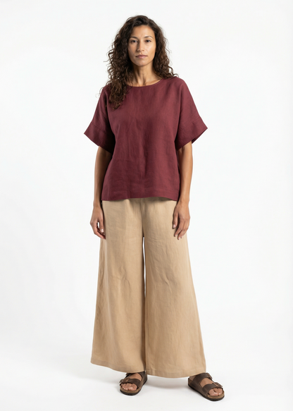 Woman wearing a burgundy top and beige pants on a white background