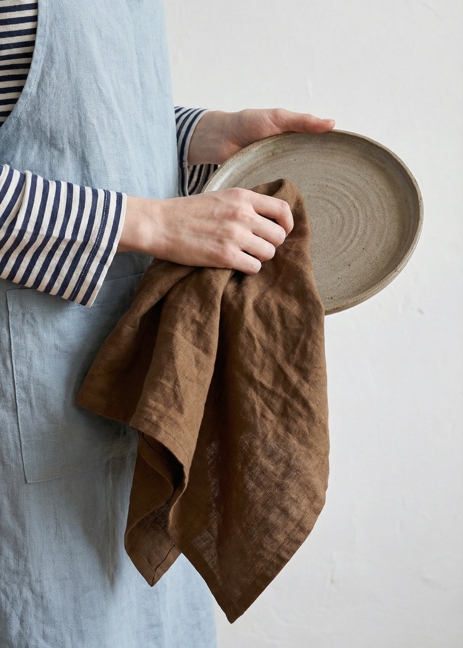 Person holding a brown towel and a woven basket against a white background