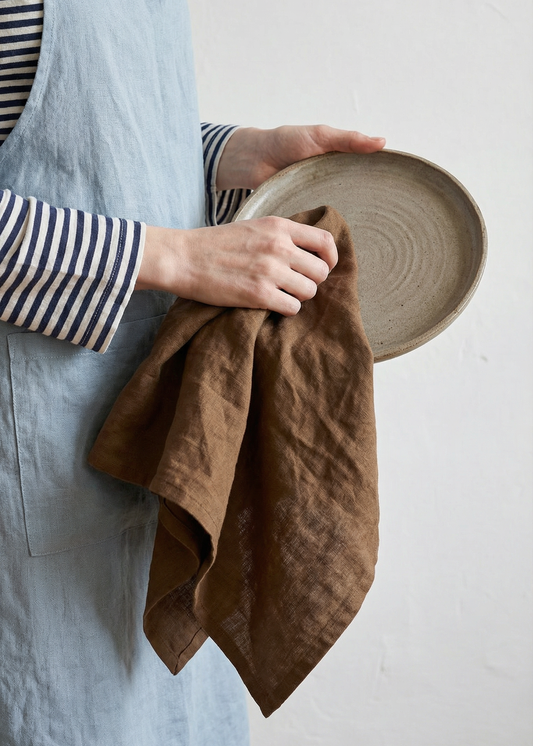 Person holding a brown towel and a woven basket against a white background