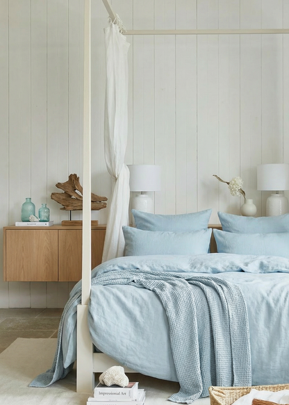 Bedroom with light blue bedding and wooden furniture.