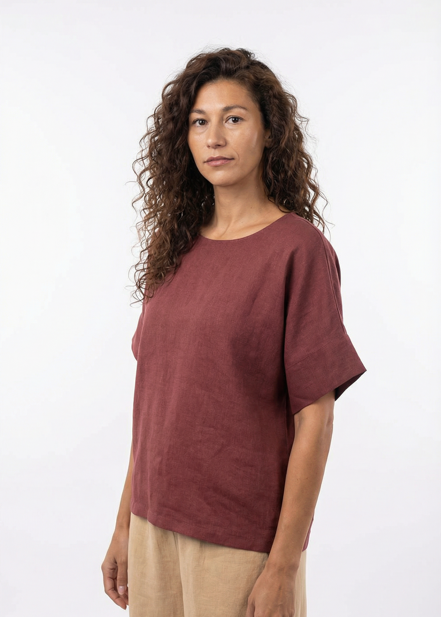Woman wearing a maroon t-shirt and beige pants on a white background