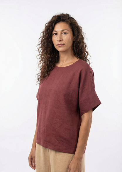 Woman wearing a maroon t-shirt and beige pants on a white background