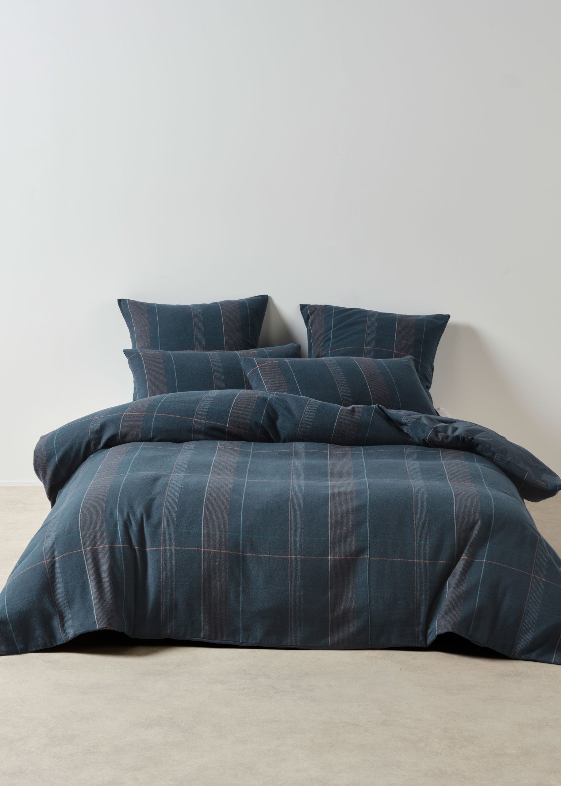 Blue plaid bedding set on a bed against a plain wall
