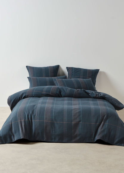 Blue plaid bedding set on a bed against a plain wall