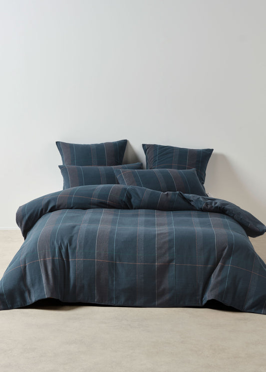Blue plaid bedding set on a bed against a plain wall