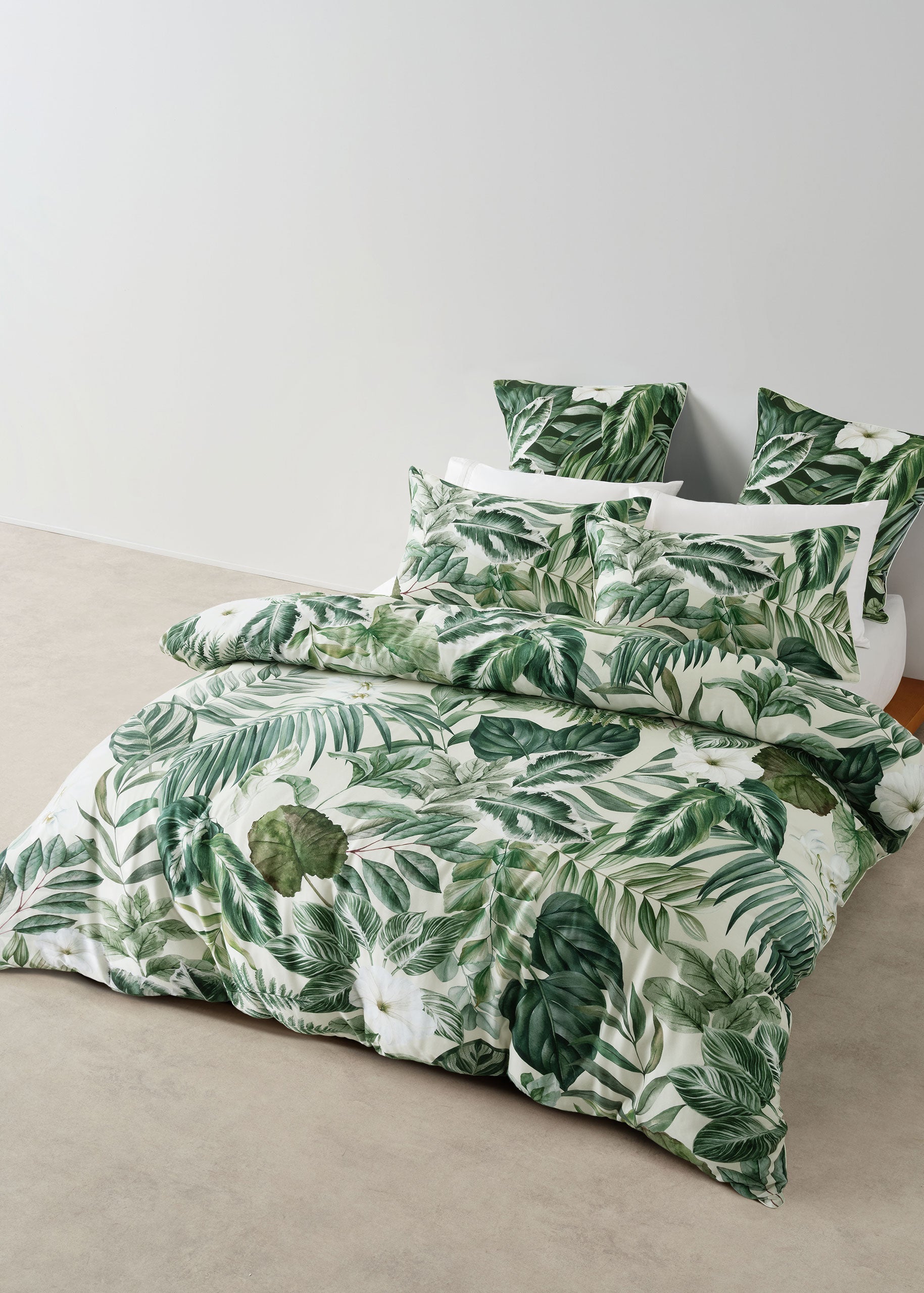 Tropical leaf patterned bedding set on a bed with a plain background