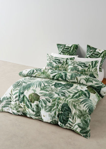 Tropical leaf patterned bedding set on a bed with a plain background