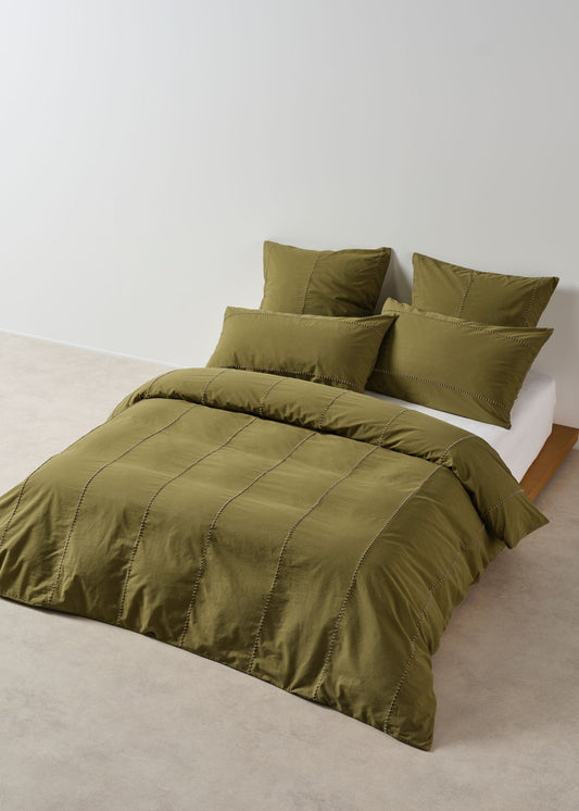 Green bedding set on a bed against a white wall