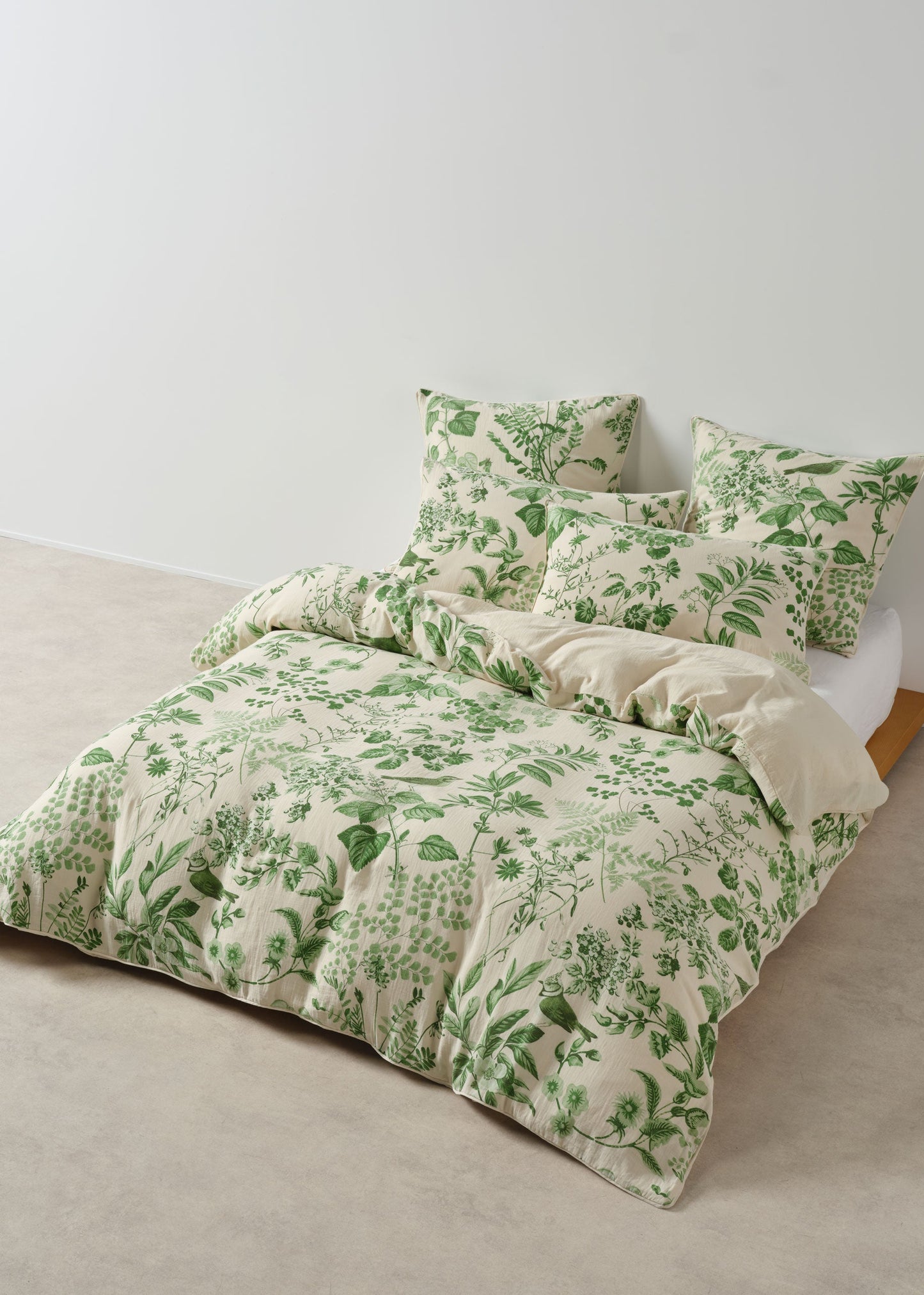 Green floral bedding set on a bed against a white wall