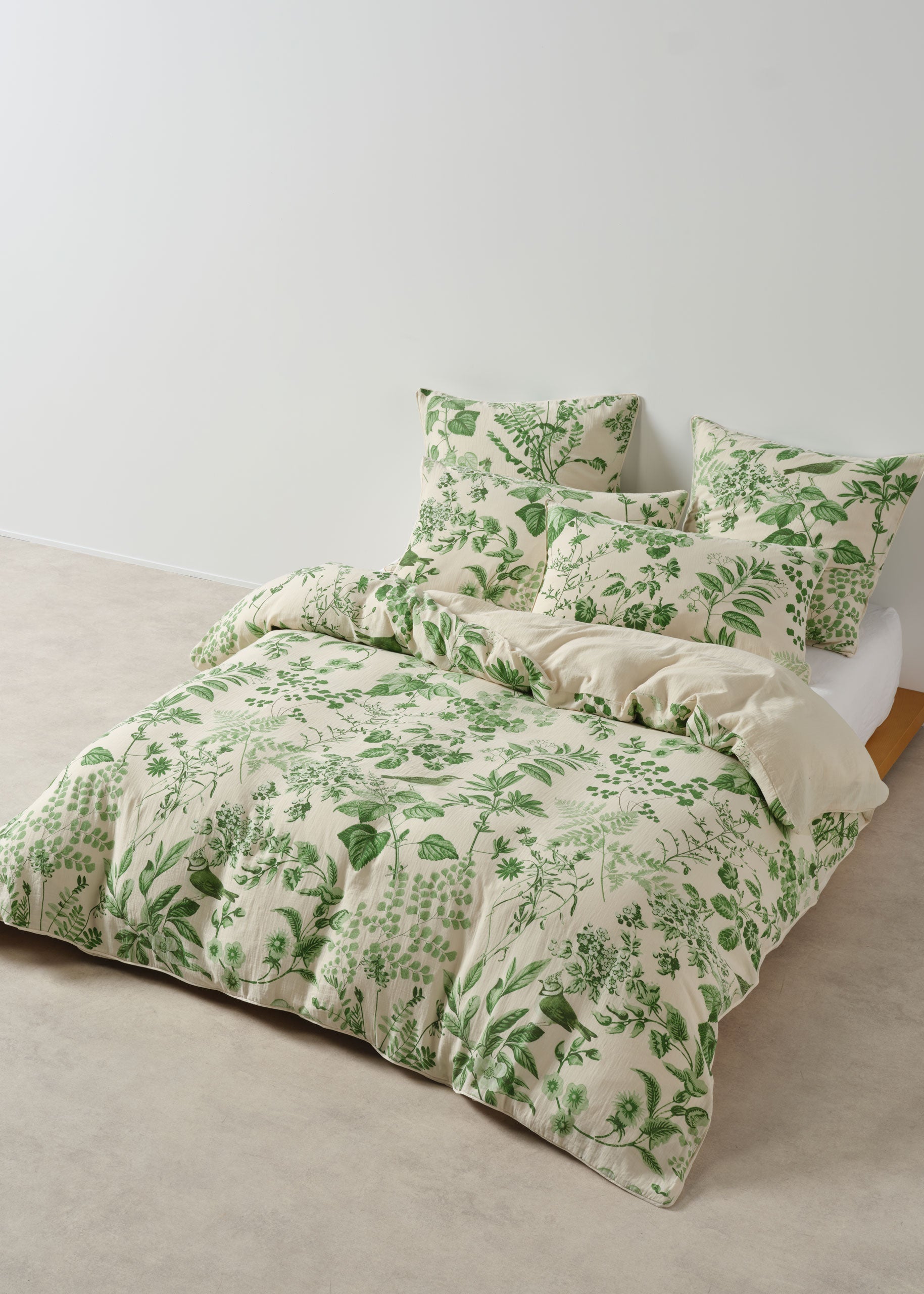 Green floral bedding set on a bed against a white wall