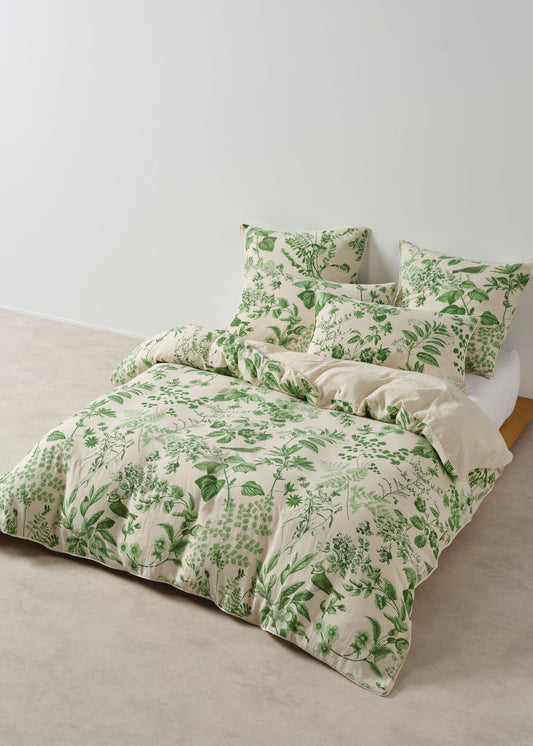 Green floral bedding set on a bed against a white wall