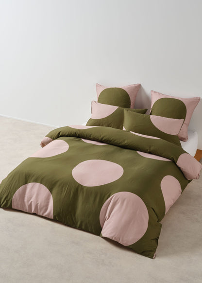 Green and pink polka dot bedding set on a bed with matching pillows.