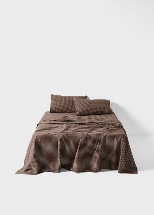 Brown checkered bedspread with matching pillows on a white background