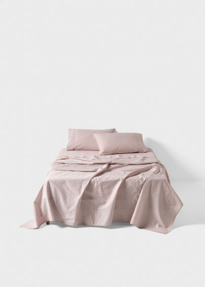 Pink bedding set on a bed with a plain background
