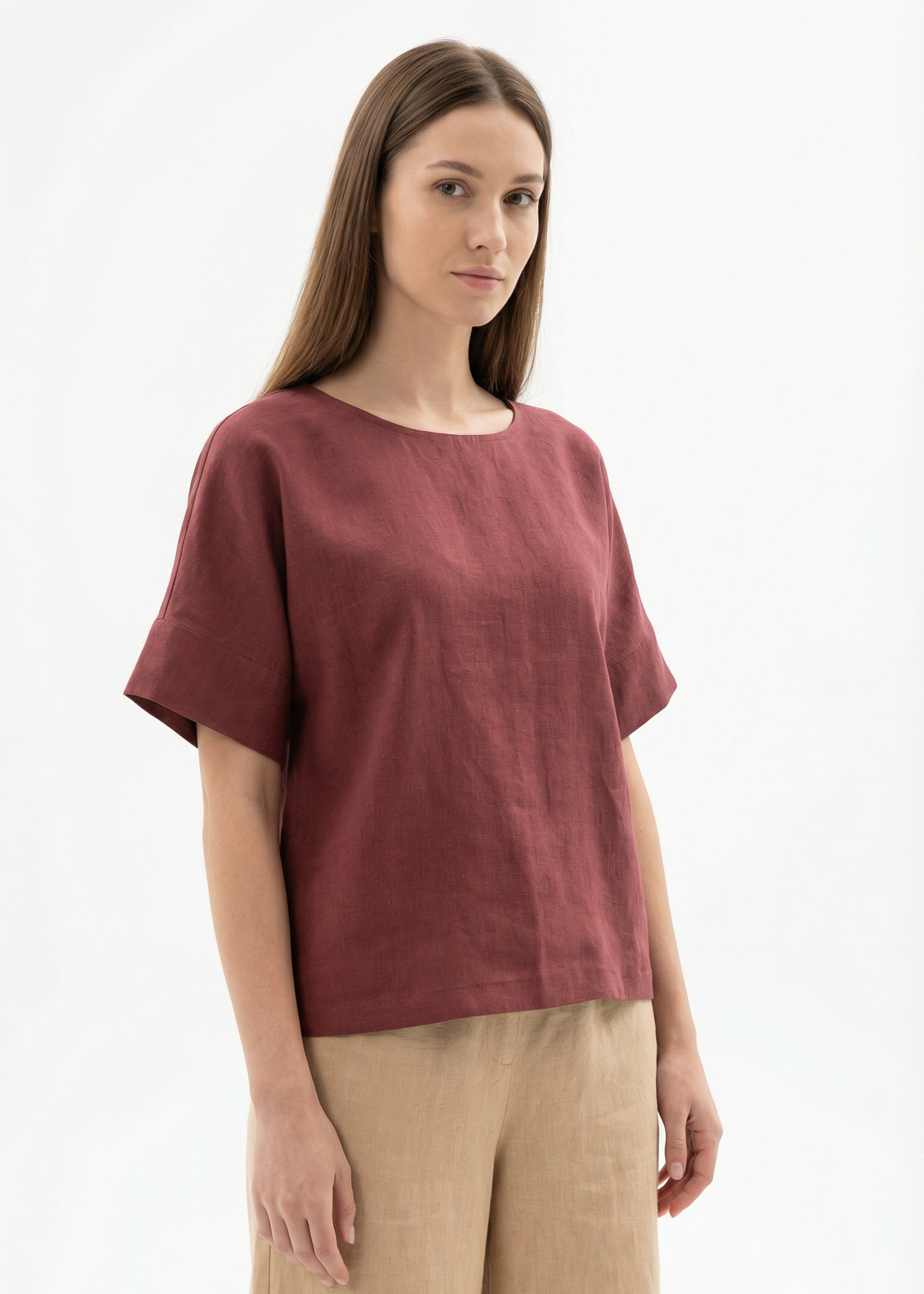 Woman wearing a maroon top and beige pants on a white background