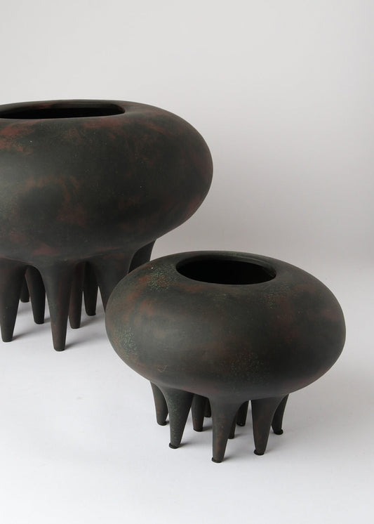 Two black ceramic pots with unique designs on a white background