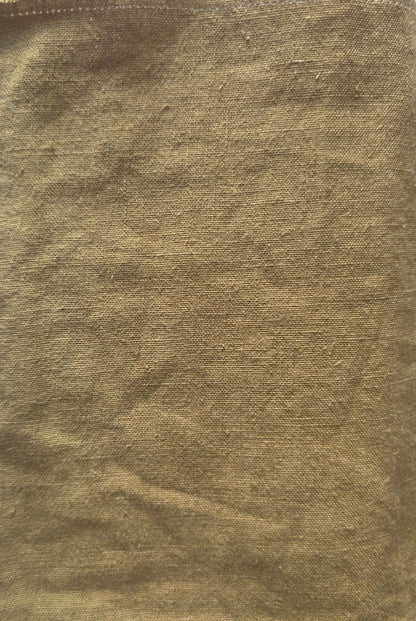 A square piece of textured tan or ochre-colored fabric laid flat on a white lined notebook page.