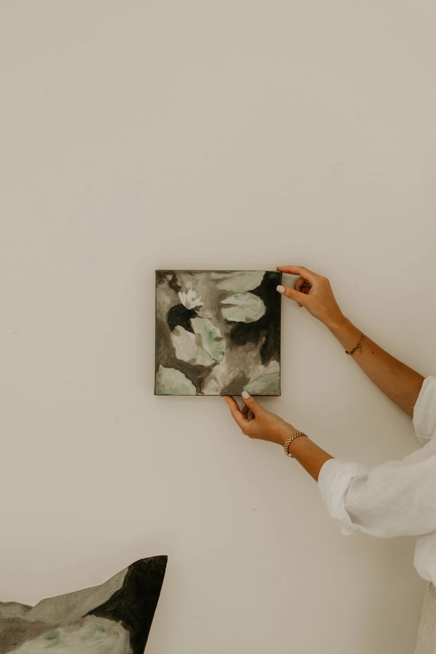 Person hanging a framed artwork on a wall