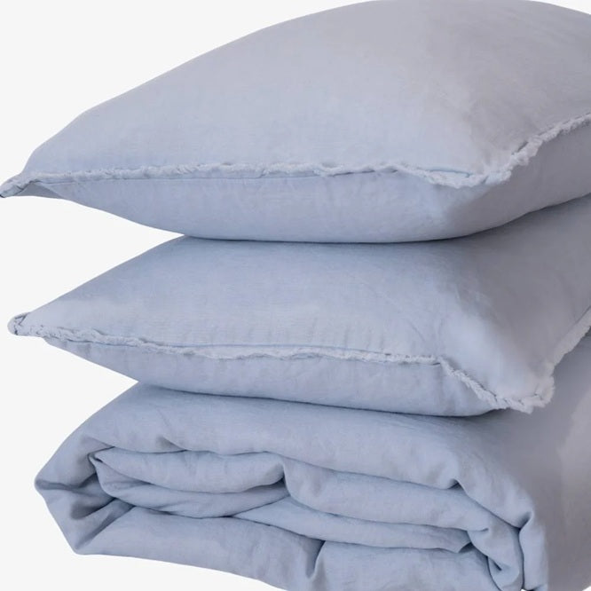 Stack of light blue pillows and a folded sheet on a white background